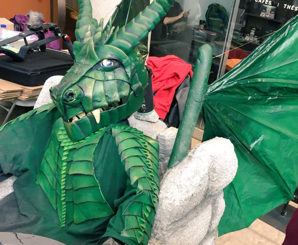 a child in a dragon costume sits in a wheelchair that has been decorated as a castle